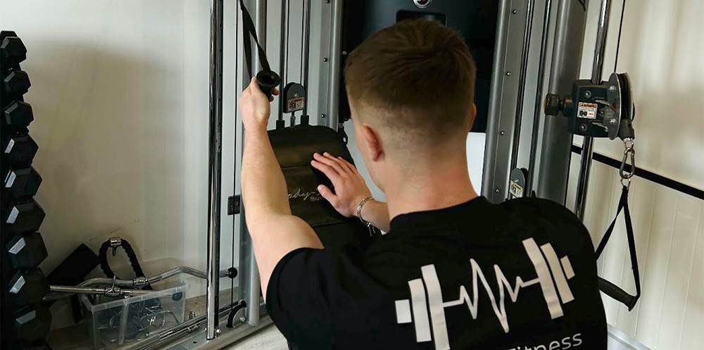 Back view of man doing exercises with cable machine