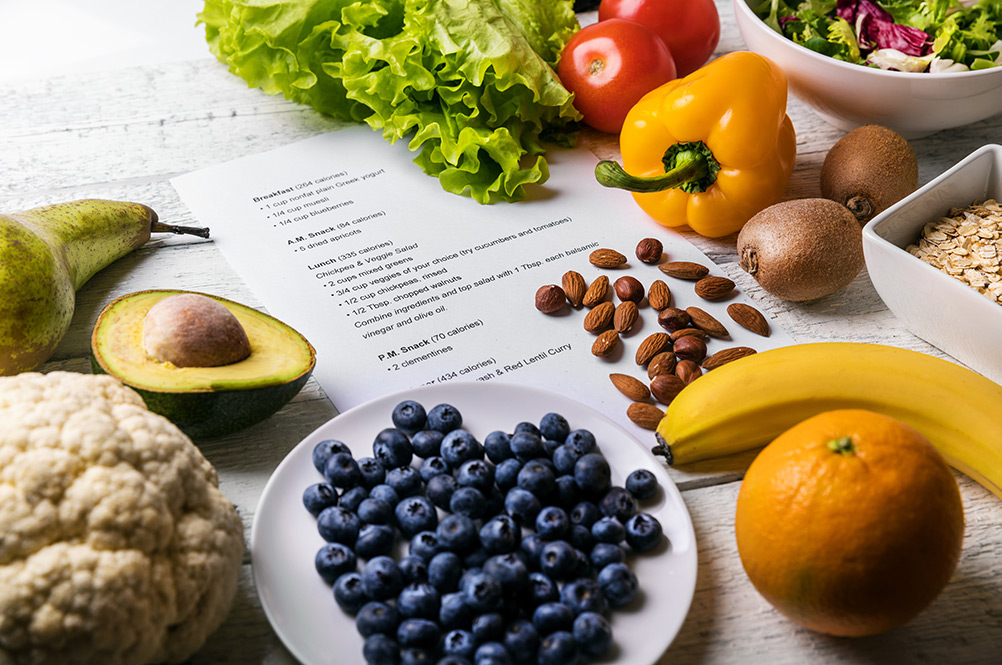 Mix of healthy food on table with printed nutrition plan