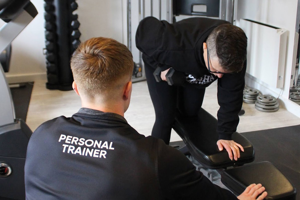 Personal trainer monitoring client dumbbell exercises